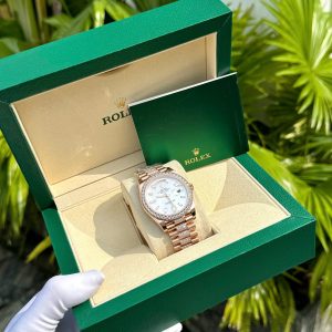 a hand wearing a glove holding a gold watch